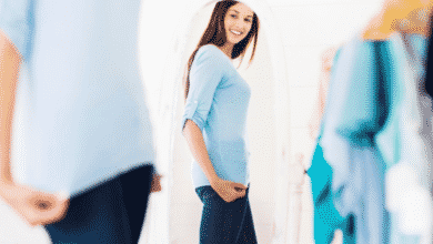 A woman looks at her herself in the mirror after fitting into new, slimmer clothing.