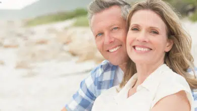 Couple smiling on the beach after facelift surgery in Hingham, MA
