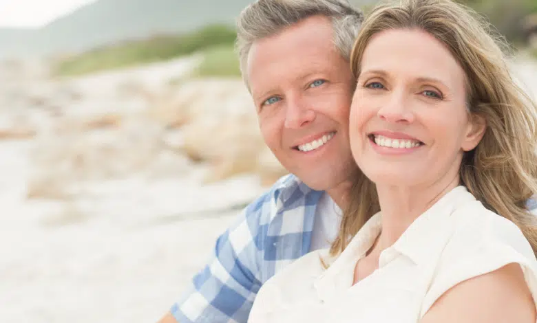 Couple smiling on the beach after facelift surgery in Hingham, MA